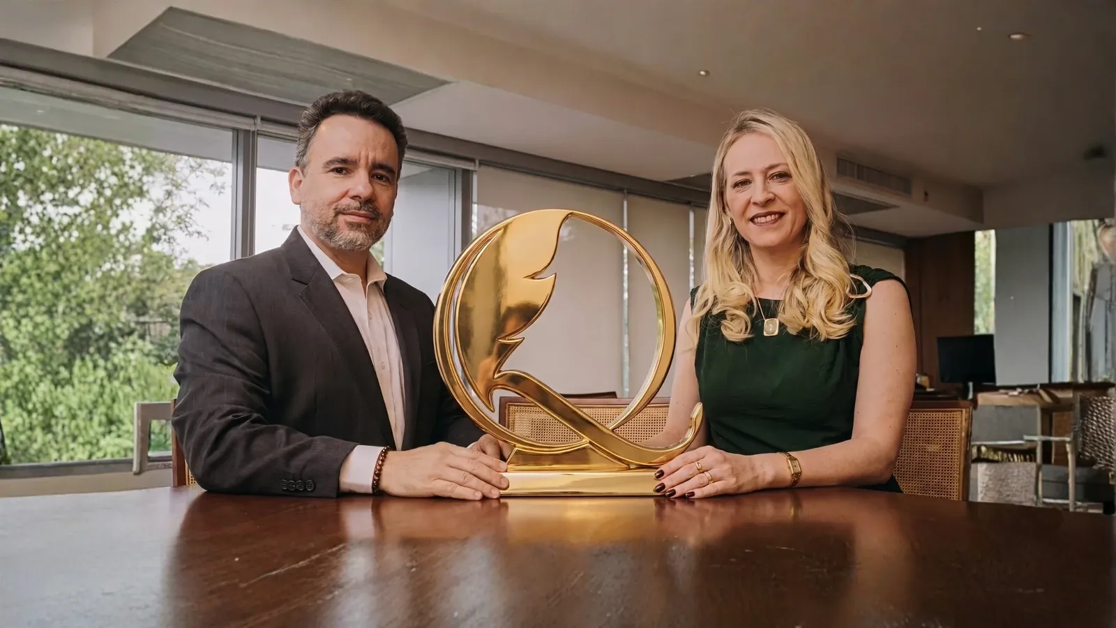 Angelson e Fabiana Quezada à mesa, com a escultura do Q dourado da Quezada entre os dois